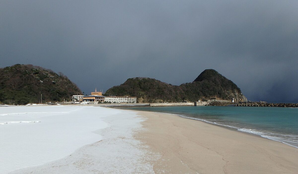 雪に覆われた冬の竹野浜と猫崎半島